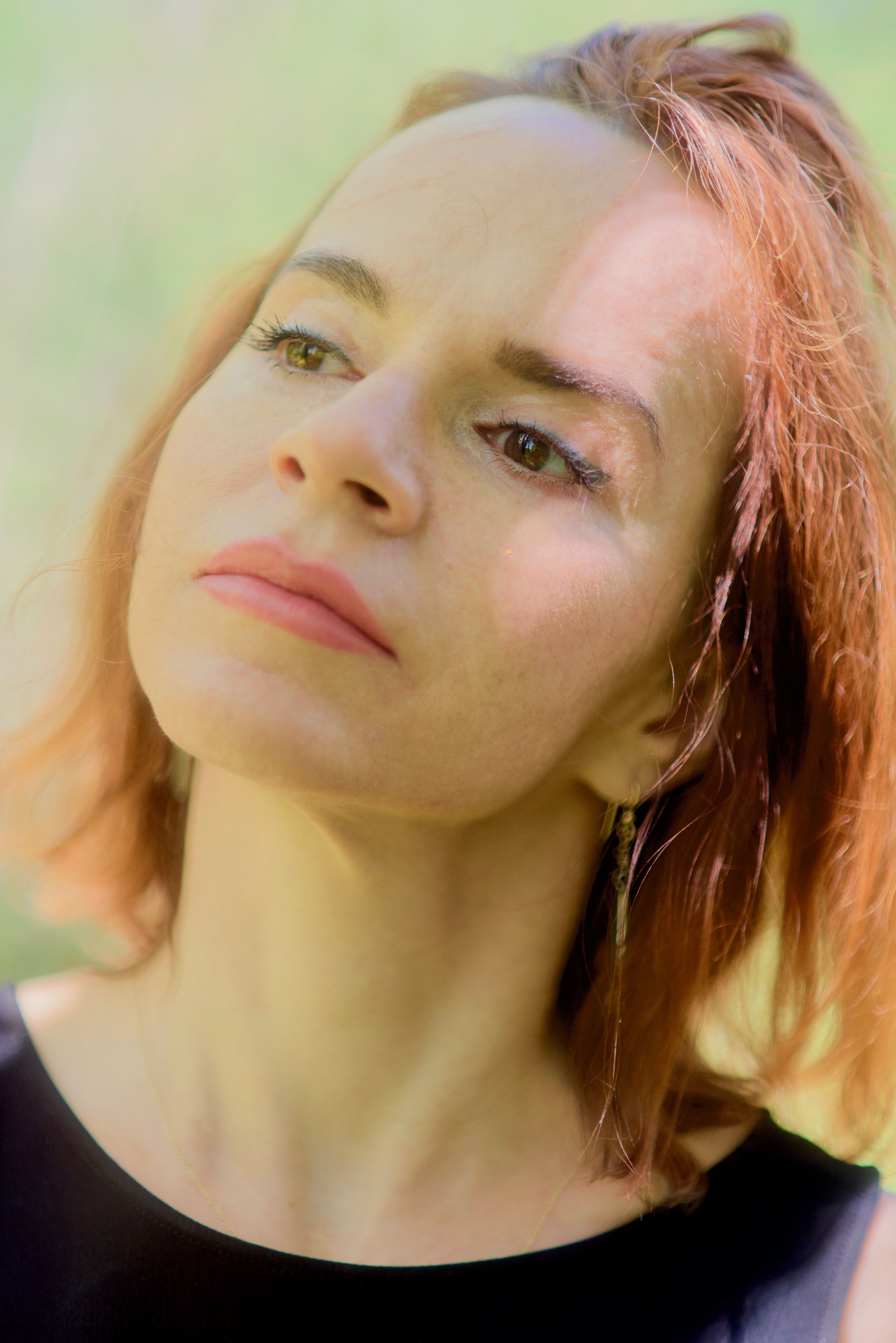 A peaceful portrait of a woman with red hair, bathed in natural sunlight. Perfect for lifestyle and beauty themes.