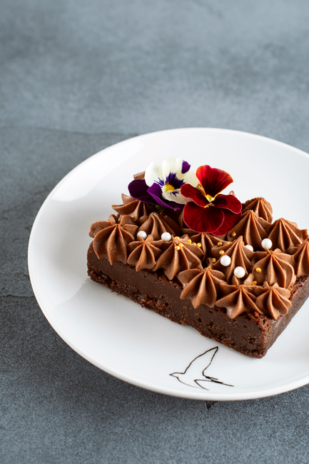 Decadent chocolate cake garnished with edible flowers. Perfect for gourmet dessert lovers.