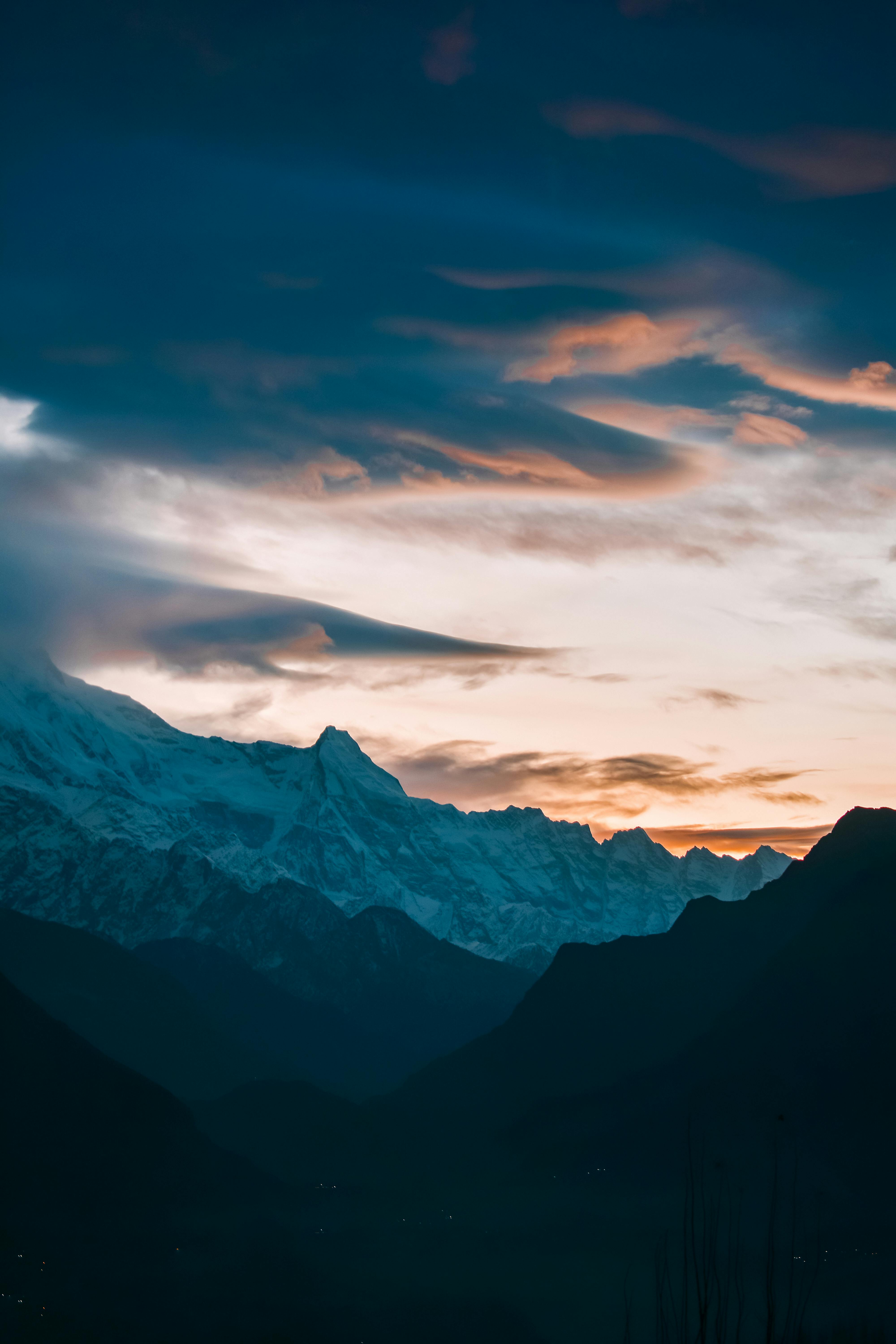 Beautiful sunrise over snowcapped mountain range with dramatic sky, perfect for nature and landscape enthusiasts.