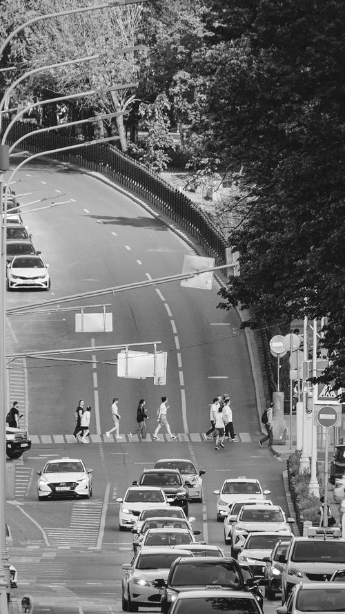 Free Black and white view of city street with cars and pedestrians at a crosswalk. Stock Photo