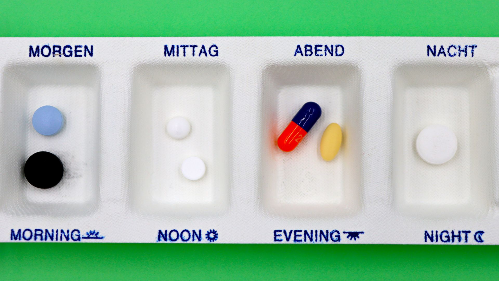 Modafinil and the Orexin System: Unlocking Alertness A daily medication organizer with pills for different times, set against a green backdrop.