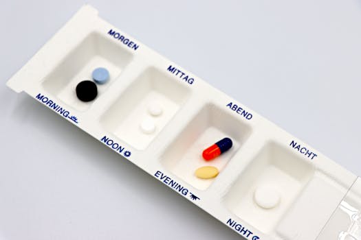 Close-up of a daily medication organizer, labeled in English and German, containing various pills.
