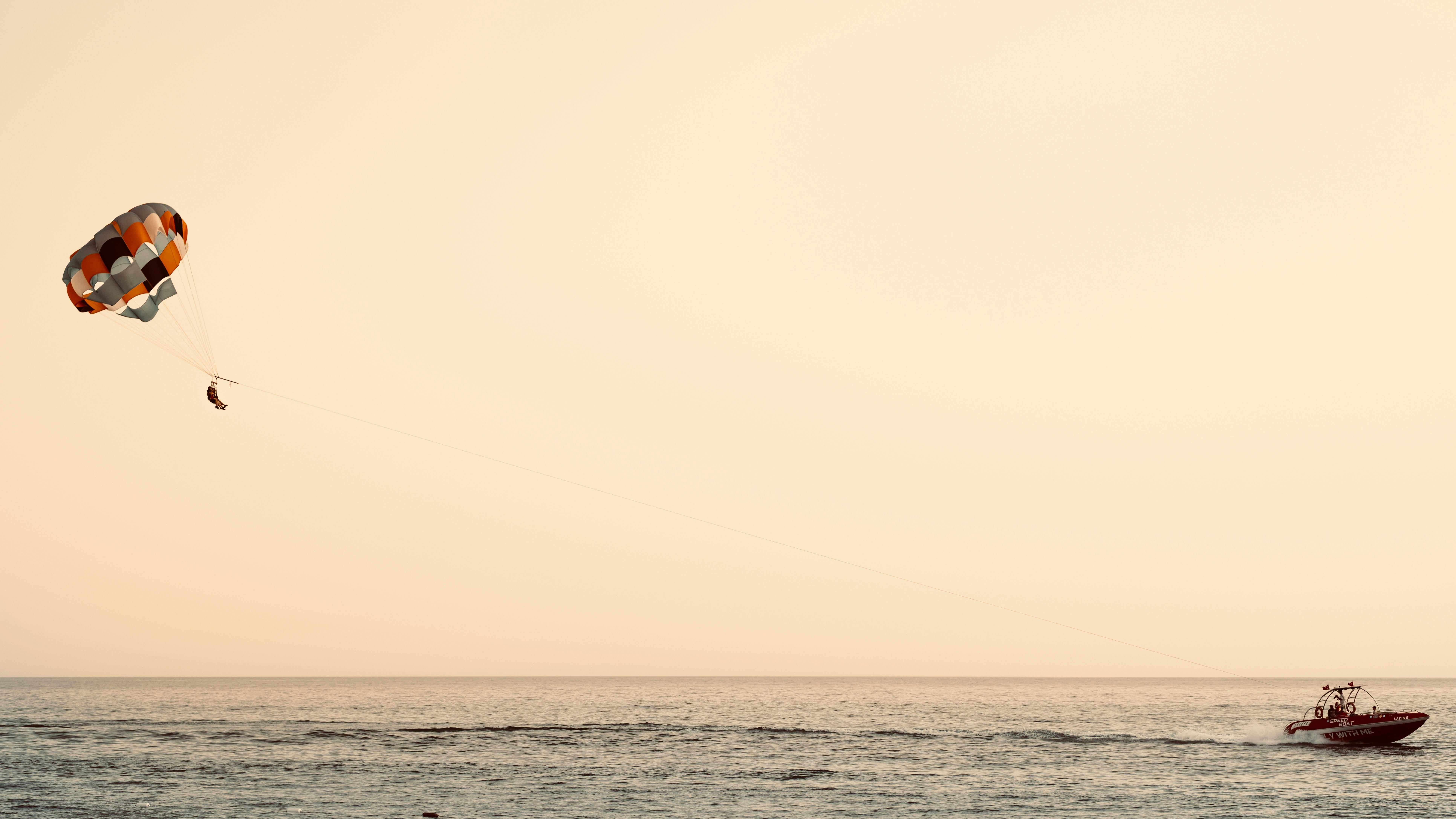 Experience the thrill of parasailing high above the ocean with a colorful parachute and speedboat.