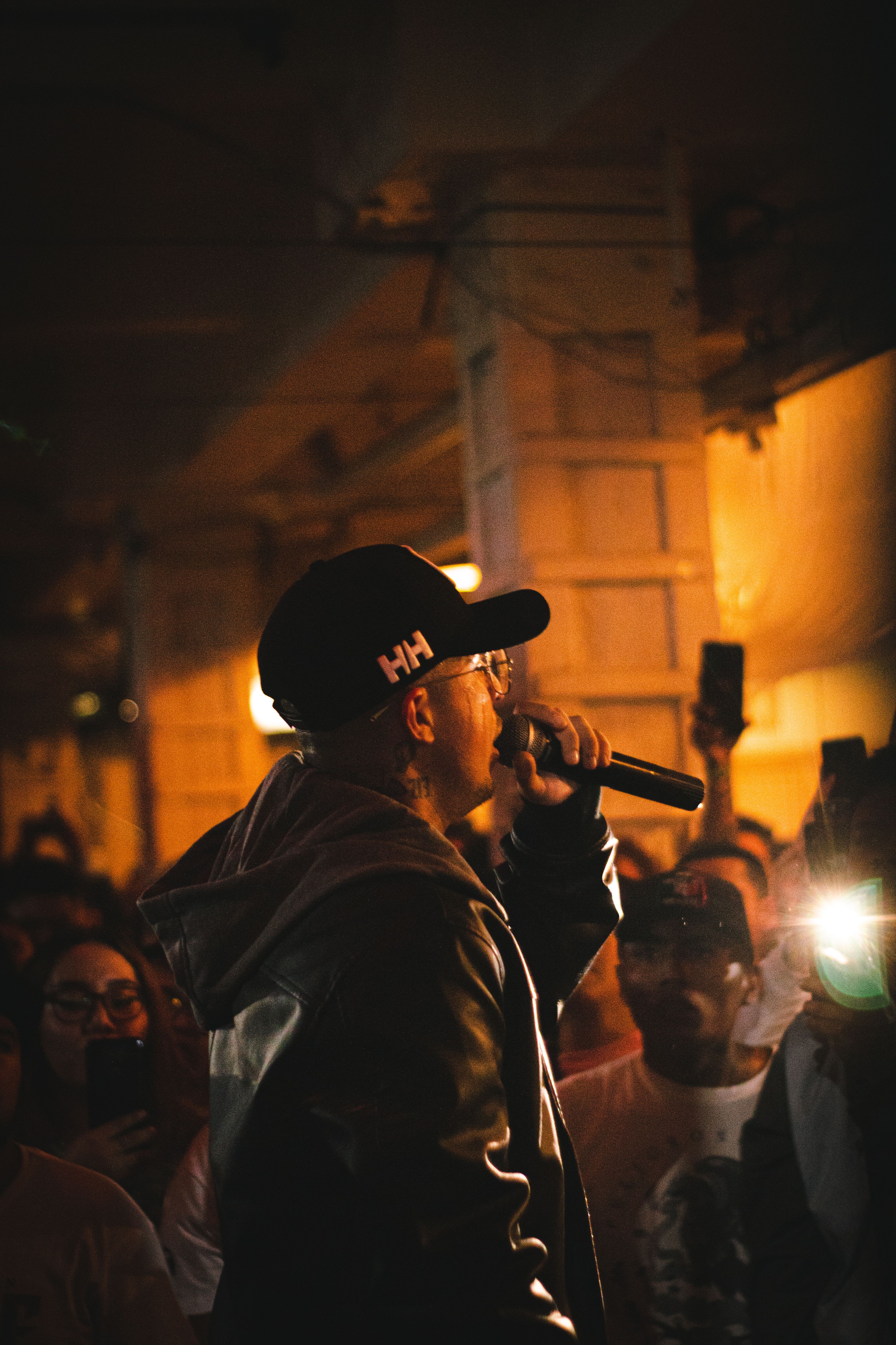 A rapper performing into the crowd under amber light