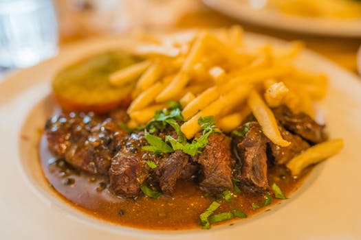 Delicious steak and crispy fries on a plate, garnished with herbs for a mouthwatering meal.