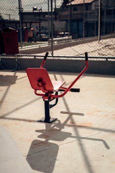 A red exercise machine at an outdoor urban gym on a sunny day.
