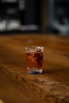 A refreshing glass of iced coffee with milk sits on a rustic wooden table, perfect for casual dining.