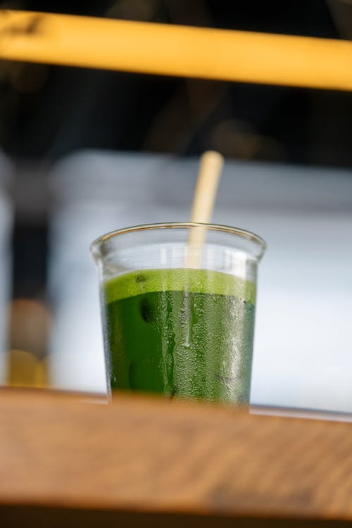 A green smoothie with a straw on top