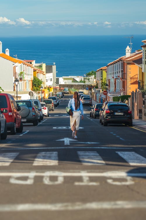 A woman walking down a street in front of the ocean