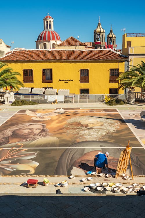 A man painting a mural on the ground in front of a building