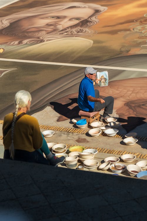 A man is painting a mural on the ground