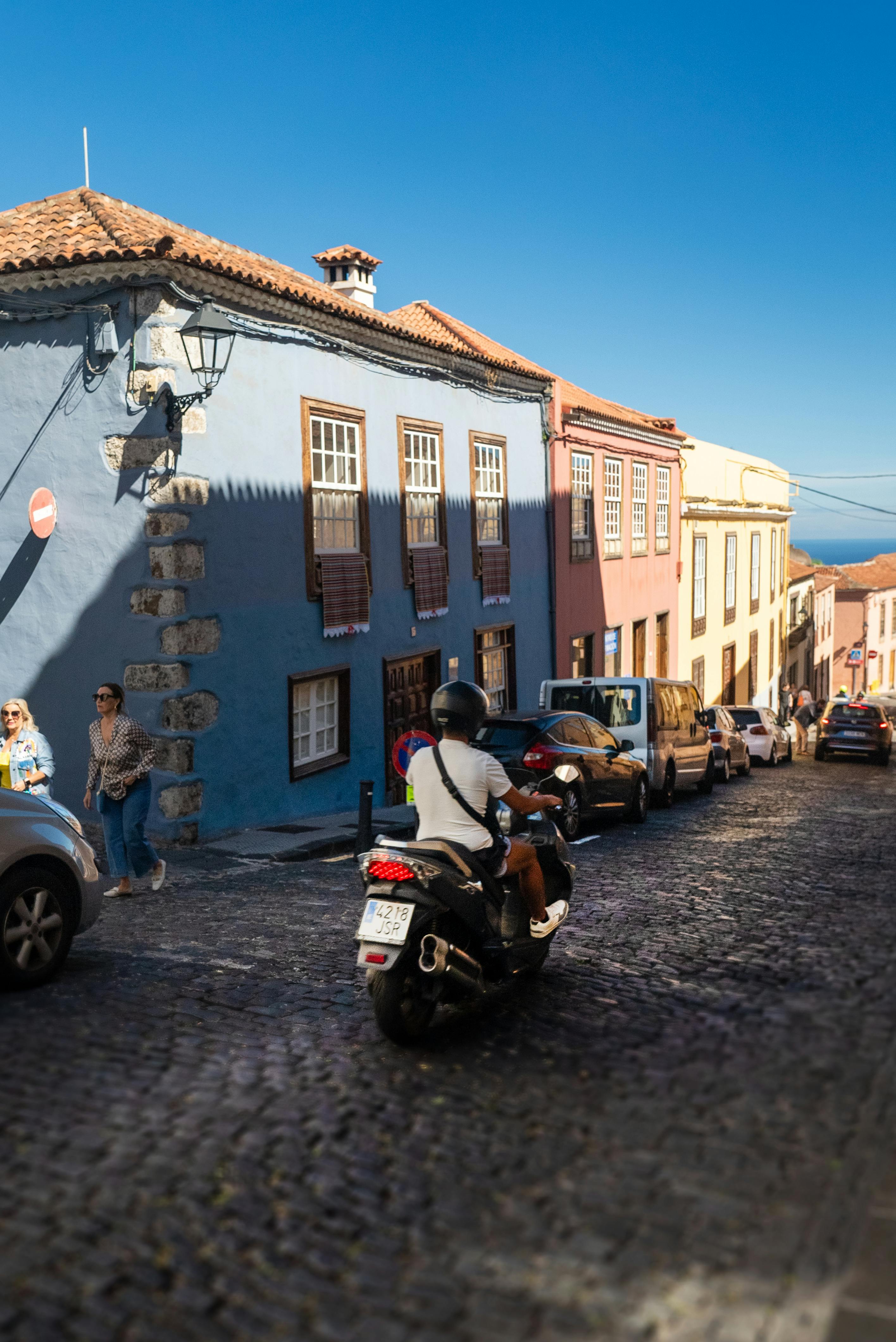 man riding motor scooter on cobblestone street in town