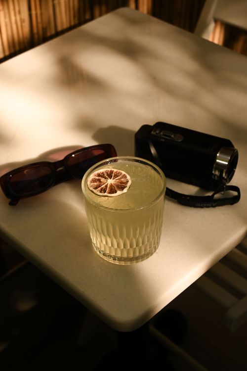 Free Lemonade in a glass on table with sunglasses and a camera, warm tones. Stock Photo