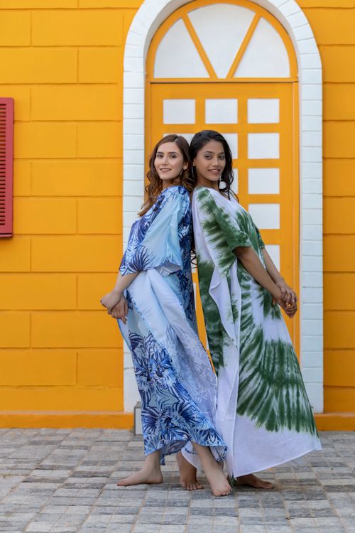 Free Two women in Jaipur wearing beautiful traditional dresses posing against a vibrant orange wall. Stock Photo