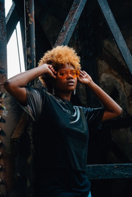 Fashionable black woman with curly hair and sunglasses posing confidently outdoors in Chicago.