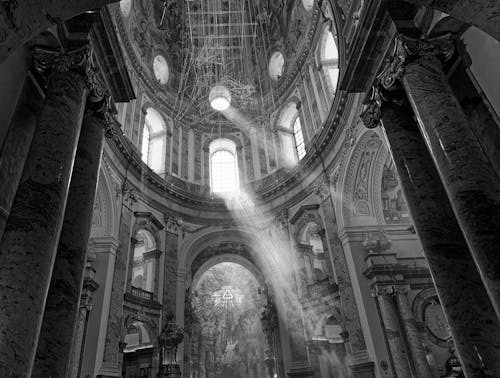 A black and white photo of a church with sun rays