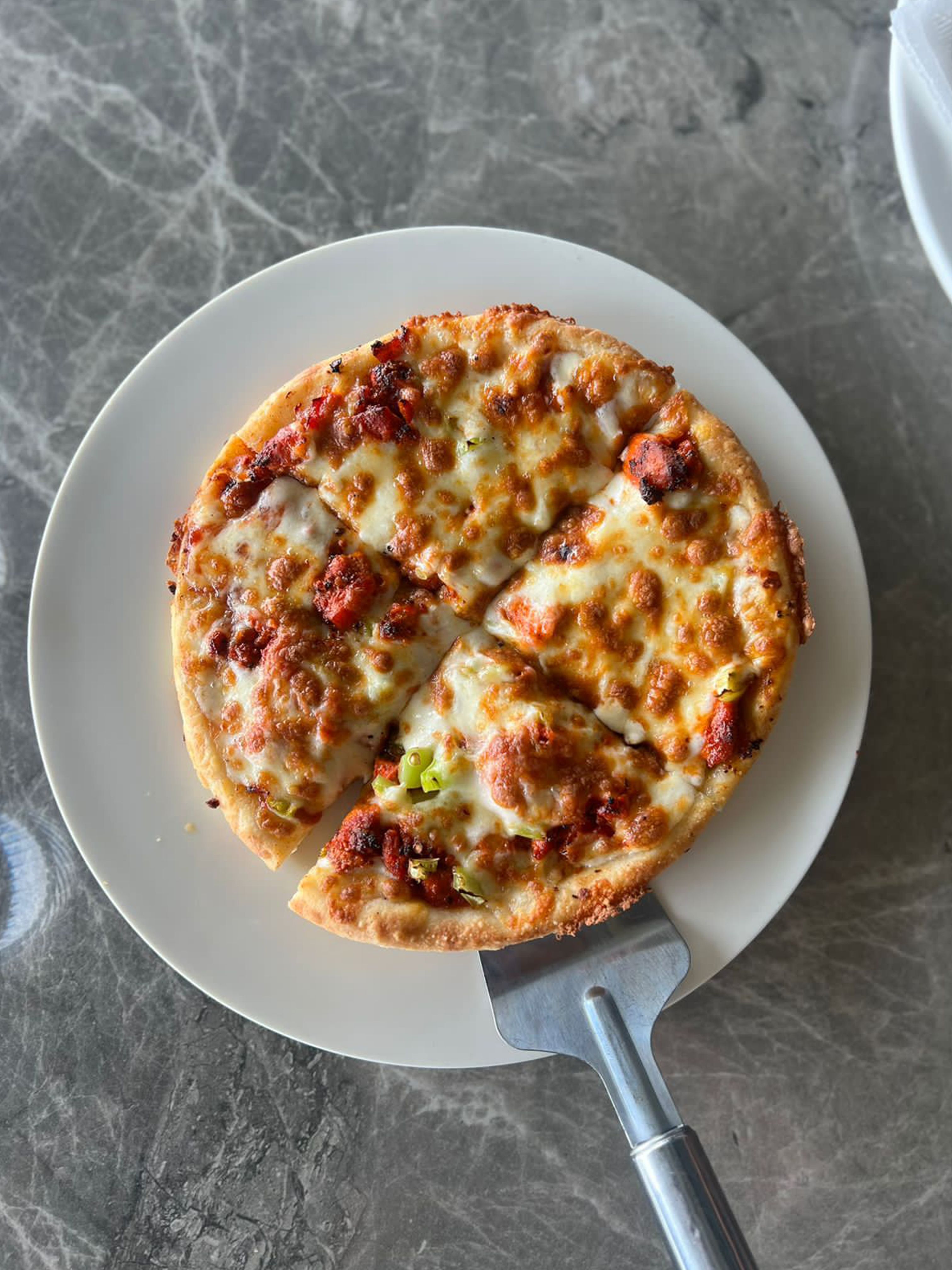 Top view of a freshly baked cheese pizza on a marble table set on a plate.