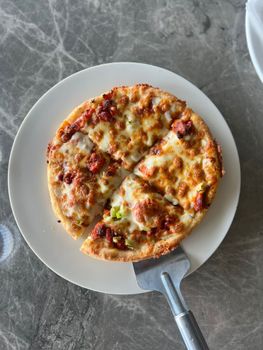 Top view of a freshly baked cheese pizza on a marble table set on a plate.