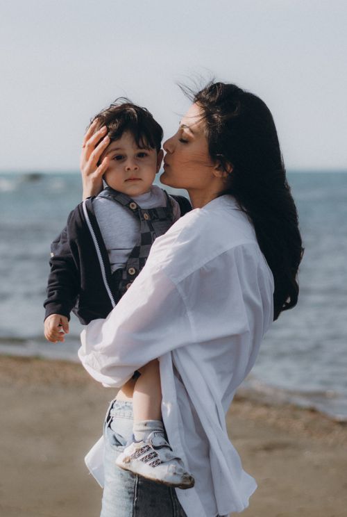 Free A touching portrait of a mother kissing her son on a beach in Baku, Azerbaijan. Stock Photo