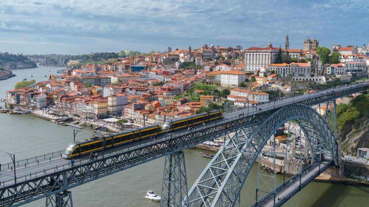 Yellow tram crossing the iron Dom Luis I Bridge in Porto with the Douro river below