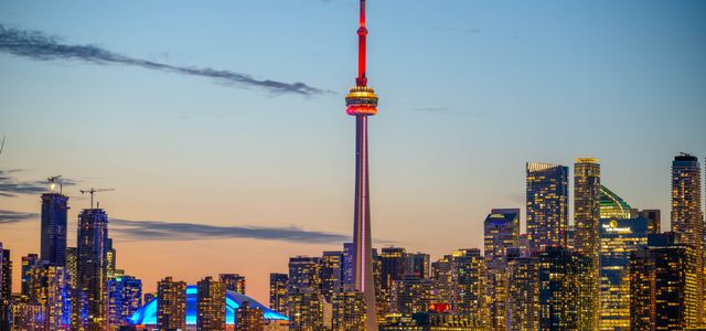 Beautiful sunset view of Toronto skyline with CN Tower and city lights reflecting on the lake.