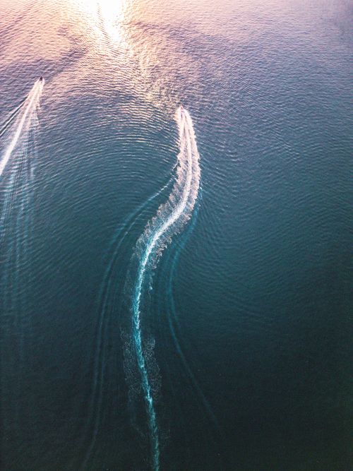 Free Aerial view capturing the dynamic movement of jet skis creating patterns on ocean water during daytime. Stock Photo