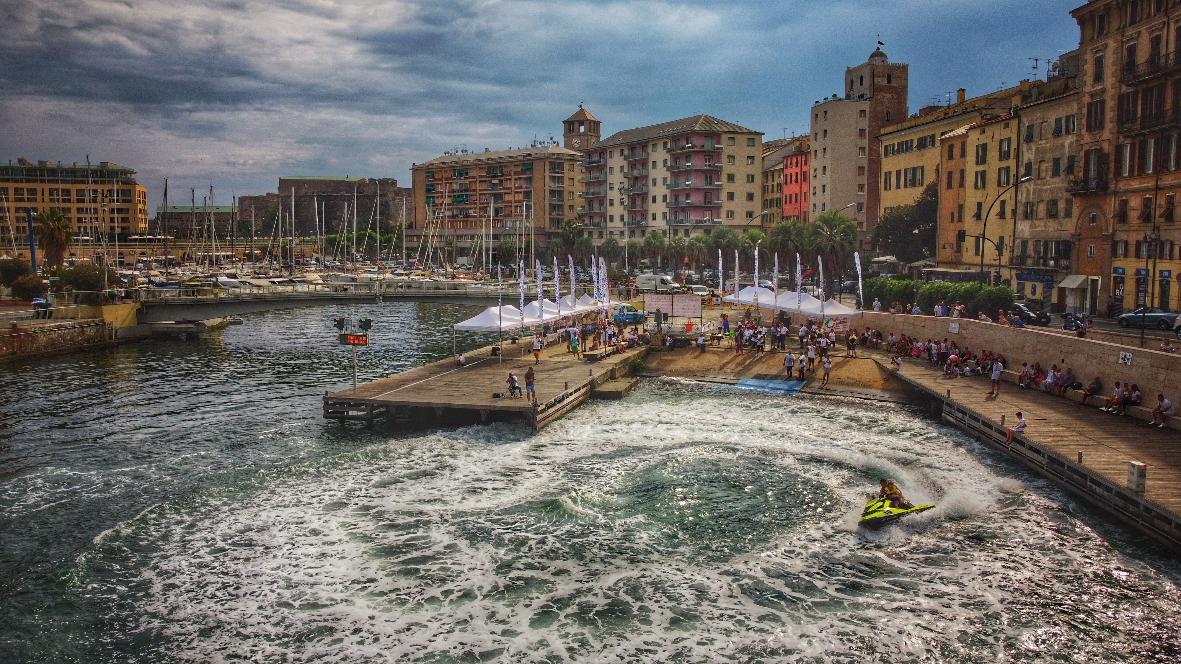 A lively coastal city with people enjoying a pier and a jet ski ride in summer.