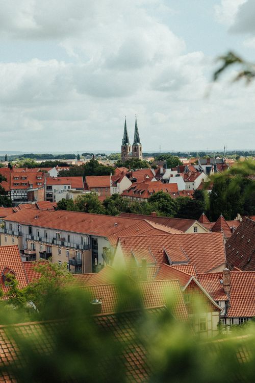 Free Scenic view of Quedlinburg's red rooftops and distant cathedral towers against a cloudy sky. Stock Photo