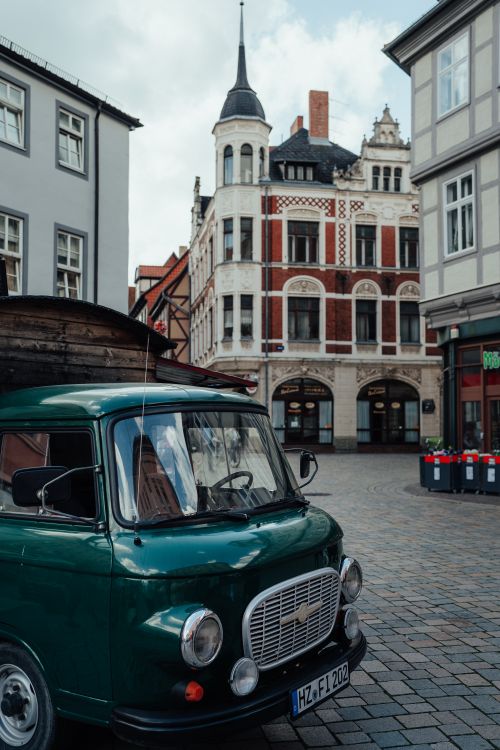 Free A vintage green van parked on a cobblestone street with historic architecture. Stock Photo