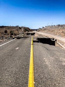 一条柏油路在沙漠景观中裂开，延伸向明亮的蓝天，突显了孤立与冒险感