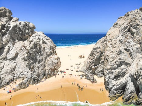 Stunning aerial view of a rocky beach with clear blue skies and tranquil ocean waters.