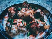 Close-up of traditional Indian dahi vada garnished with yogurt, herbs, and spices.