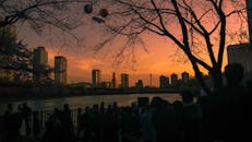 日落时分，河边的人群轮廓映衬着首尔的天际线