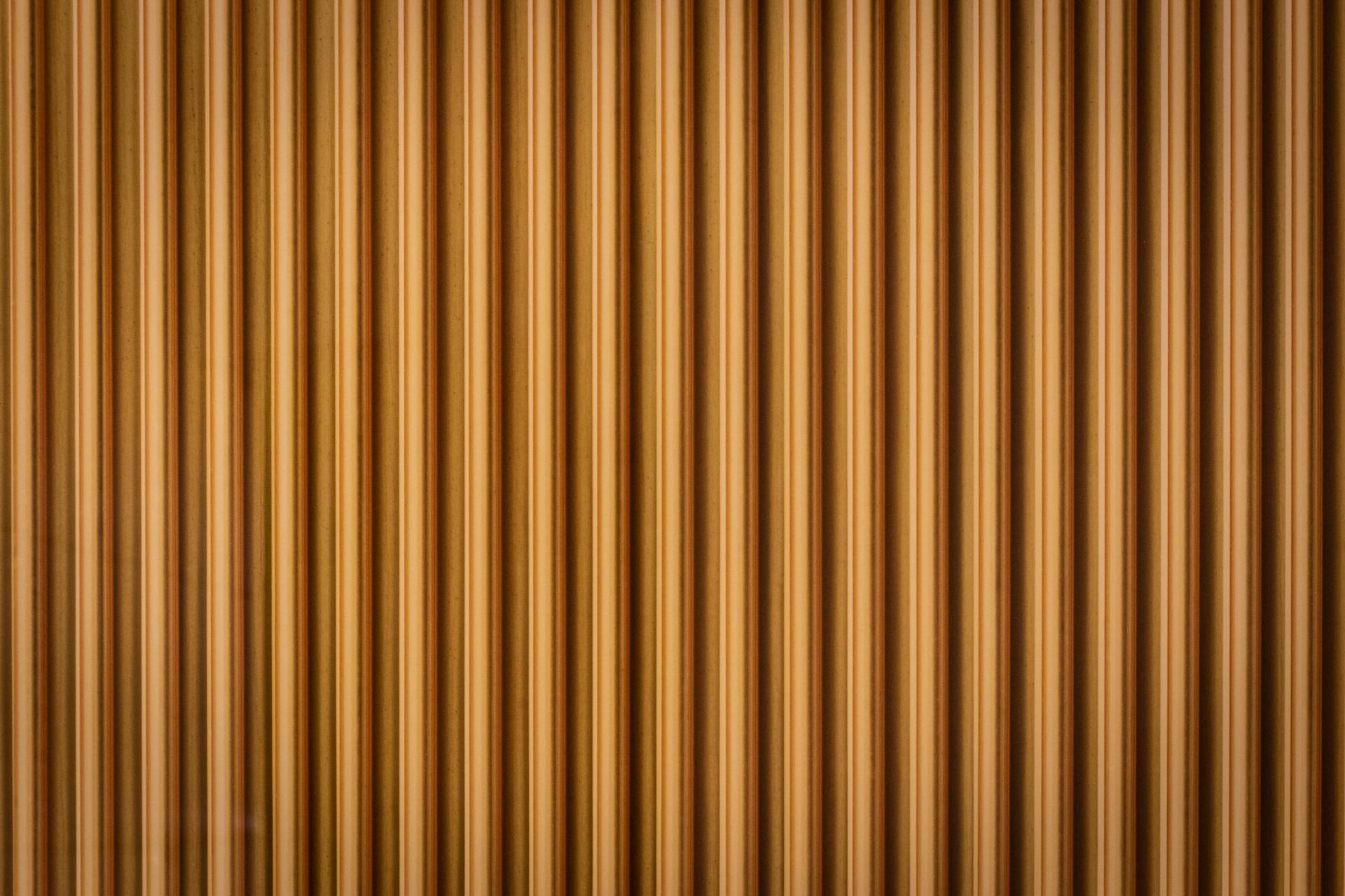 Close-up of a corrugated wooden wall with a rich brown texture, creating a geometric pattern.