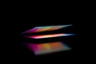 在黑暗环境中，色彩缤纷、部分打开的笔记本电脑屏幕反射着光线