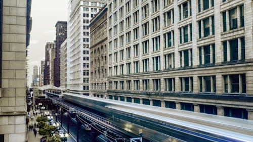 Free Time Lapse Photo of White Train Passing by Buildings Stock Photo