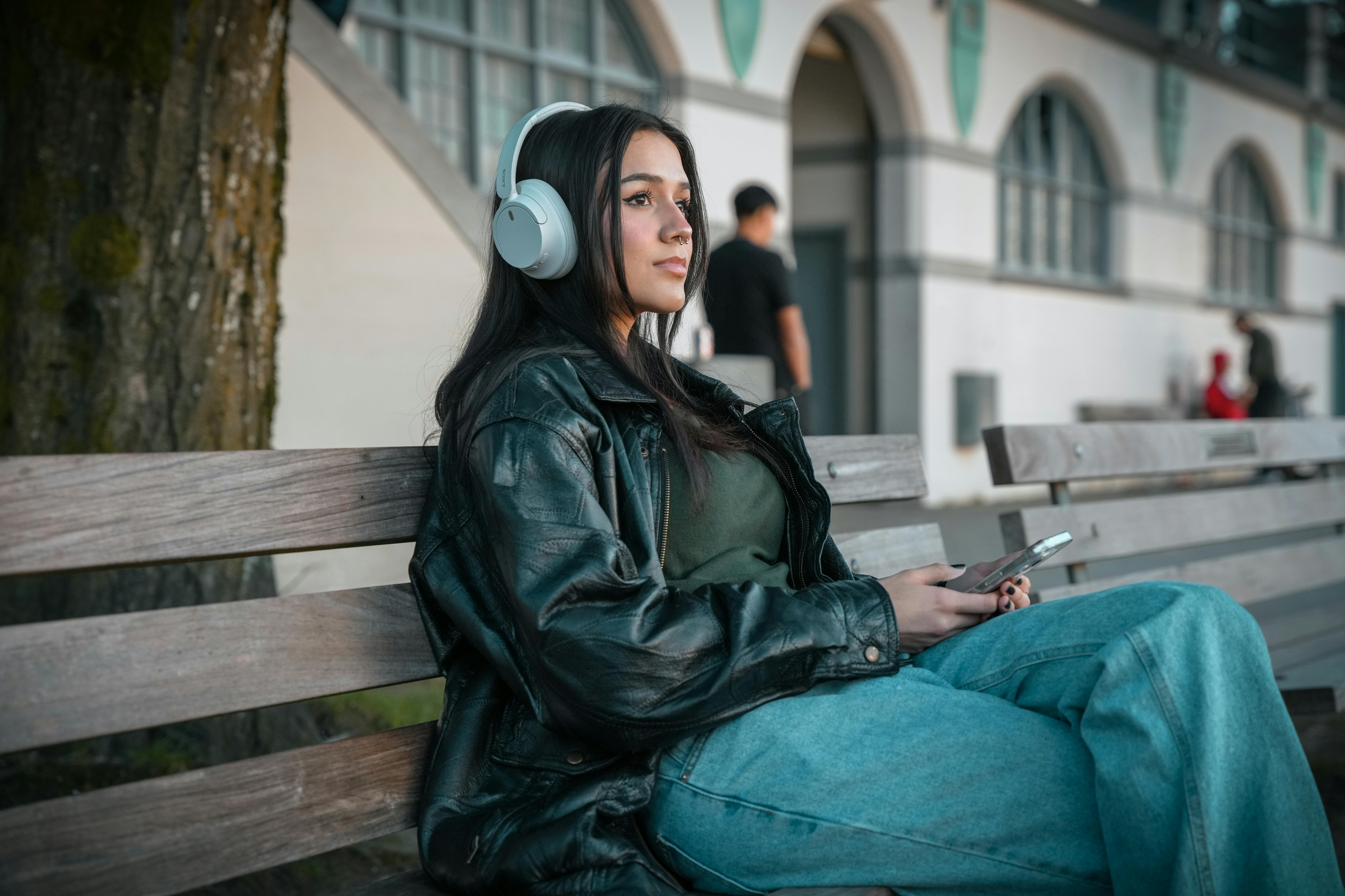 Woman With Headphones Sitting on Wooden Bench 