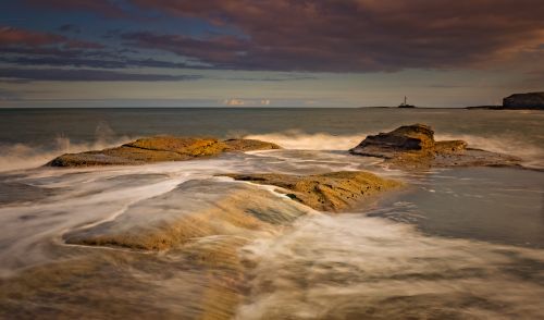 Free Captivating twilight view of seaside rocks with waves crashing. Perfect for nature enthusiasts. Stock Photo