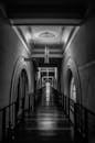 一张优雅的黑白照片，拍摄的是一条灯光明亮、空荡荡的长拱形走廊