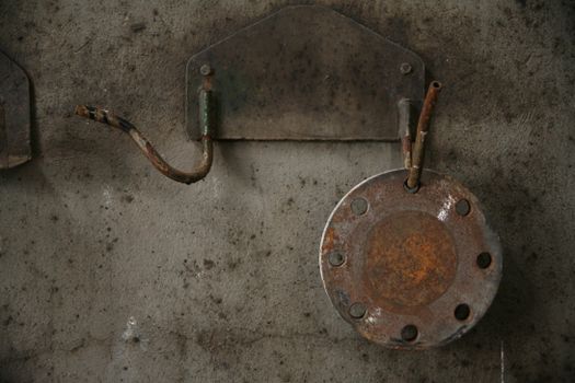 Rusty metal fixtures on a weathered concrete wall, showcasing industrial decay.