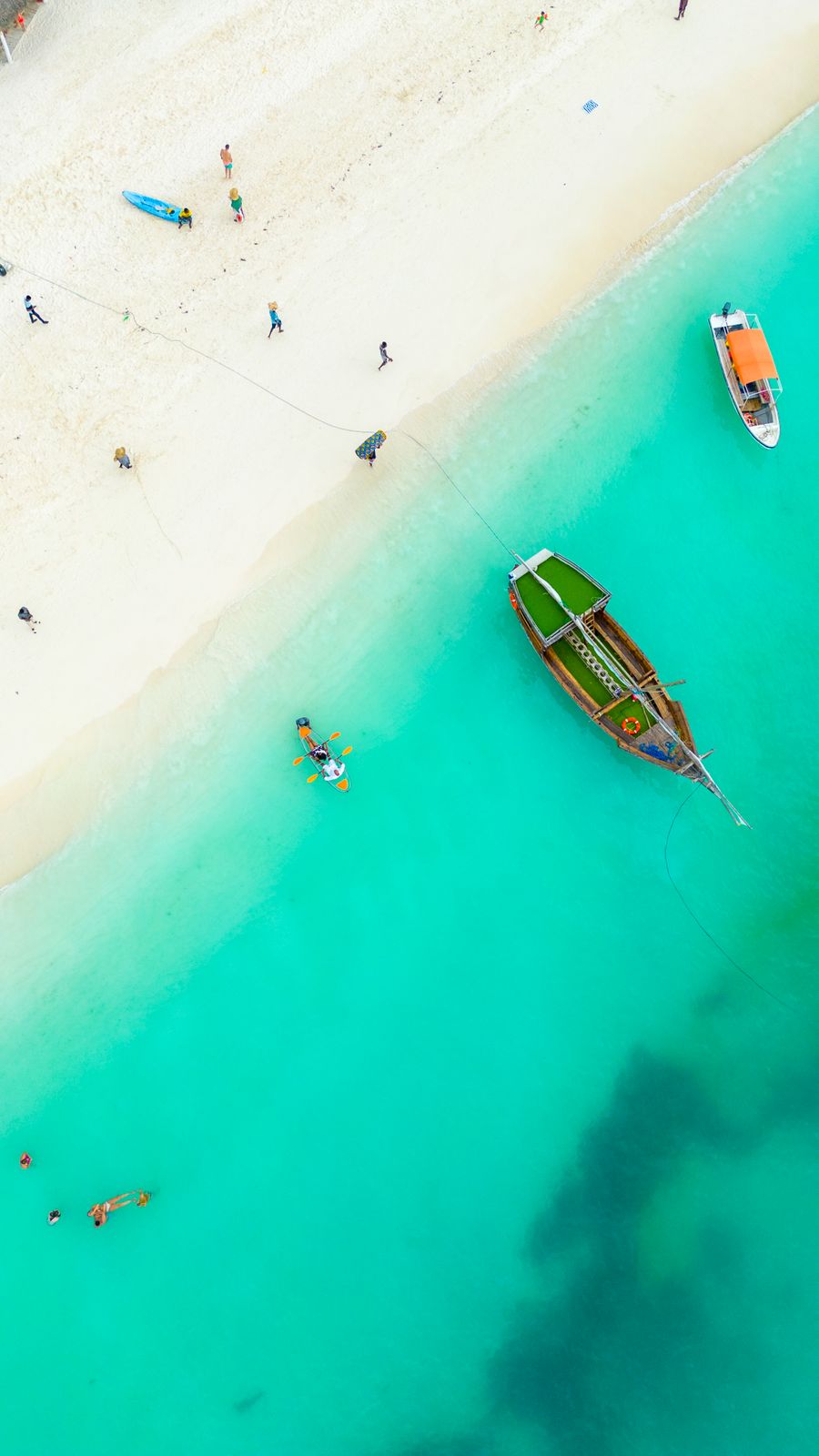 Boats and people on the ocean shore in Zanzibar at golden hour