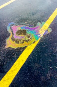 停车场内，充满活力的彩虹色石油泄漏在黑色沥青的黄线上