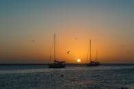 委内瑞拉格兰罗克水域上空有帆船和鸟类的宁静日落景色