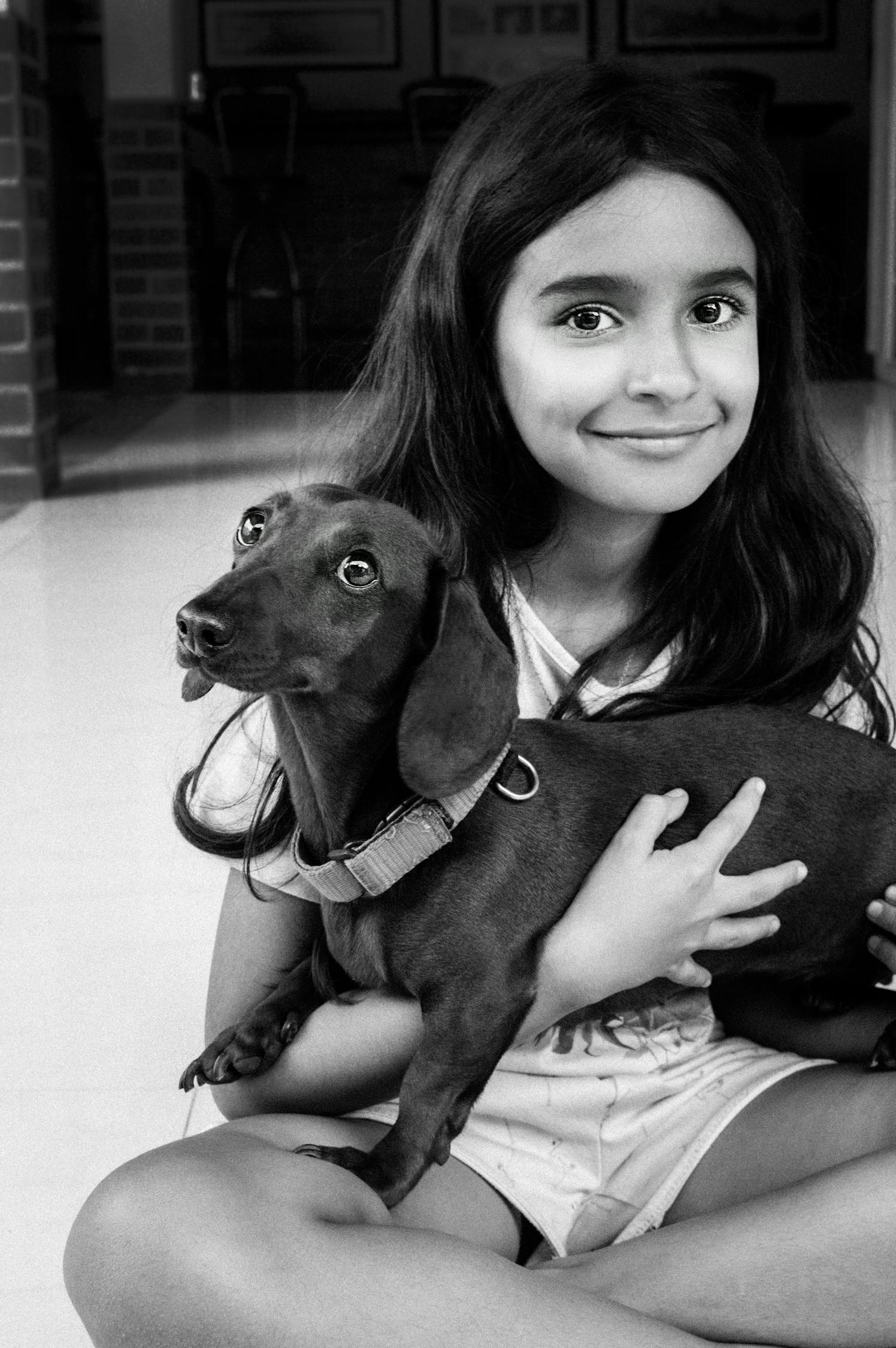 Grayscale Photography Of Smiling Girl Carrying A Dog