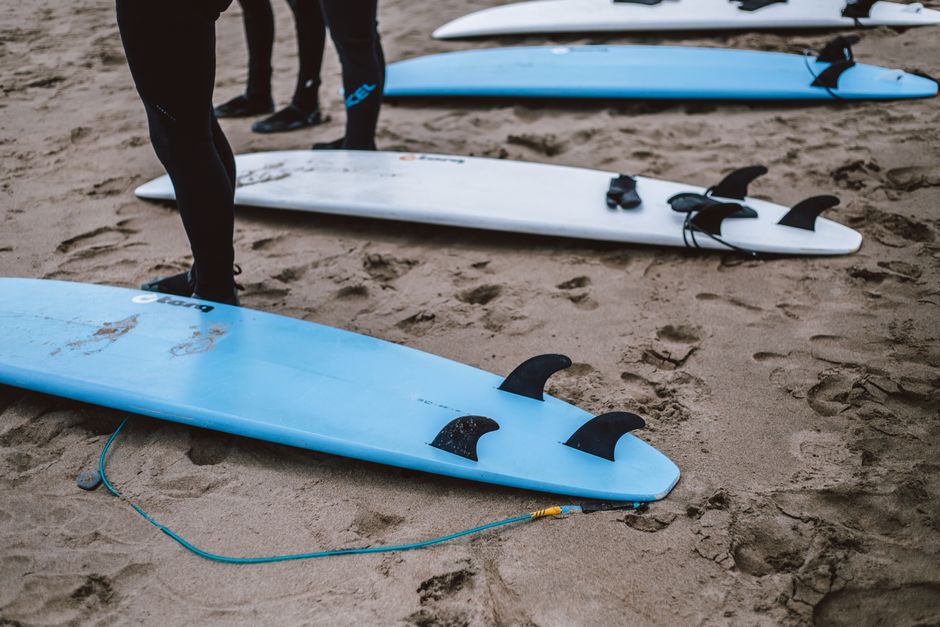 Surfboards lined up on a sandy beach, surfers prepare for ocean adventures.