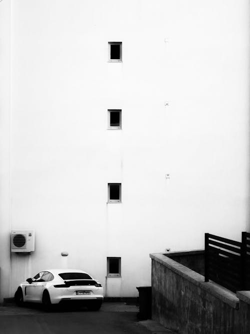 A black and white photo of a car parked in front of a building