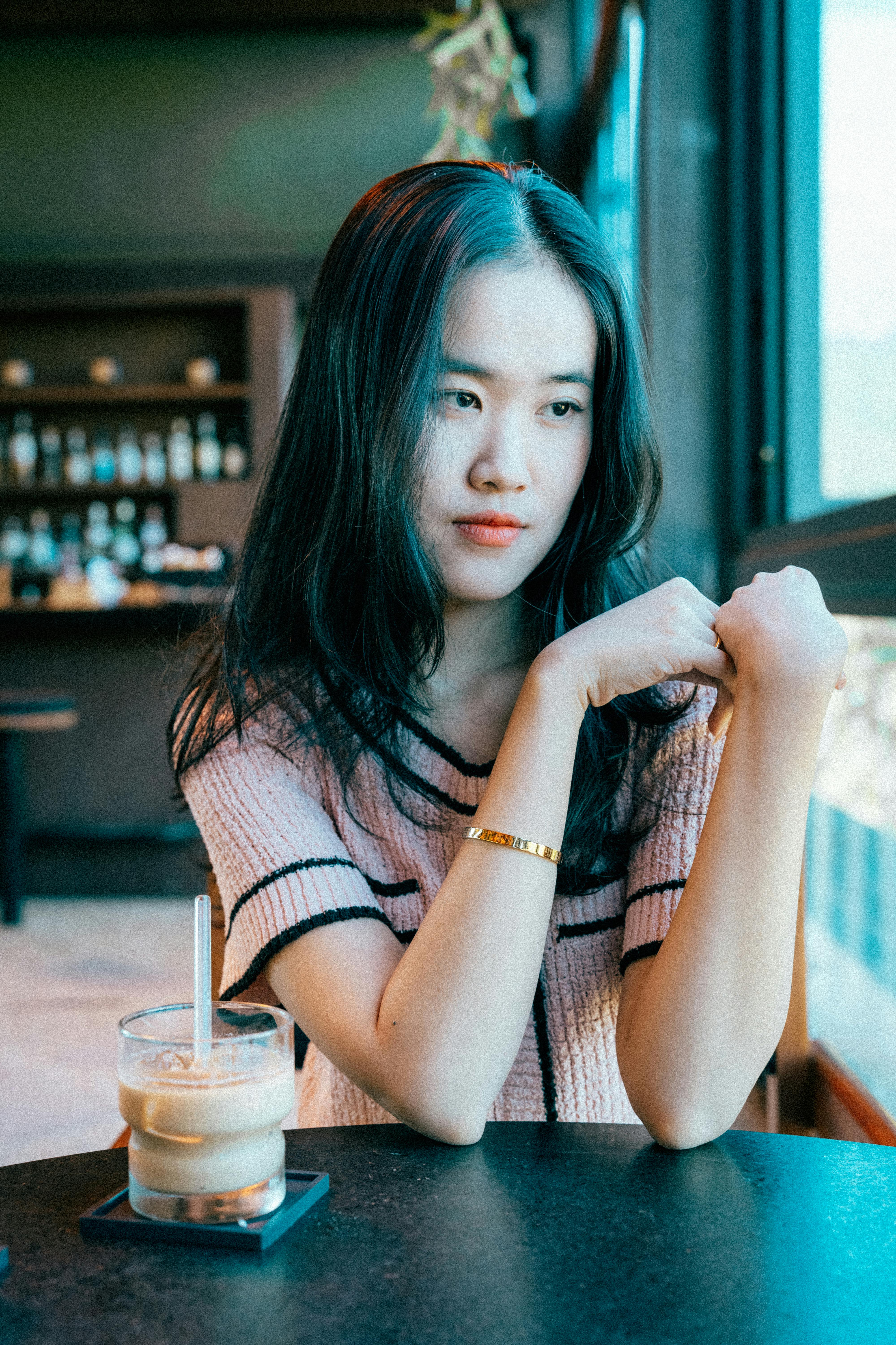 Portrait of a young woman sitting in a cozy café with an iced coffee on the table.
