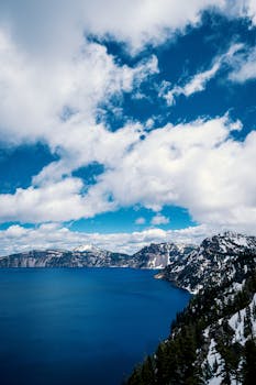 火山口湖四周环绕着白雪皑皑的山脉和蓝天，景色令人惊叹