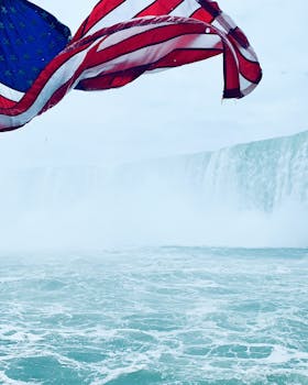 在尼亚加拉瀑布的薄雾水面上，充满活力的美国国旗迎风飘扬，象征着自由与自然