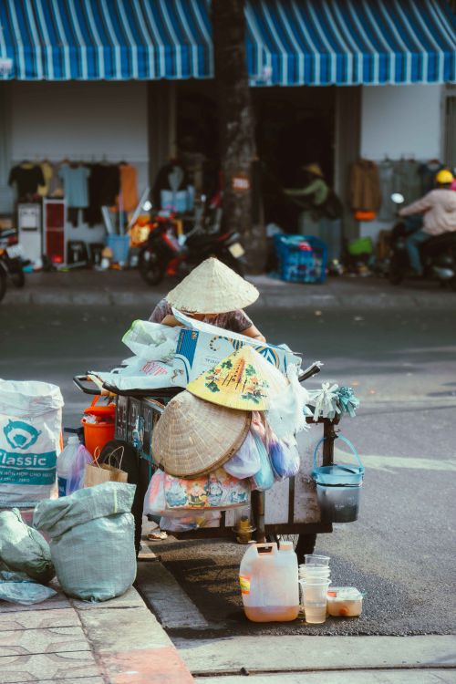 Free Street vendor with conical hats selling goods in Ho Chi Minh City market. Stock Photo